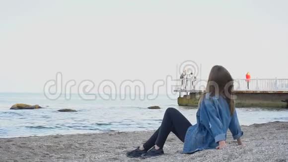 慢动作体贴的女人看海景听冲浪在温暖的夜晚坐在沙滩上视频的预览图