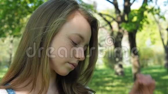 那个女孩把头发弄直了一个长着雀斑的十几岁女孩在公园里很伤心公园里一个悲伤的女孩青少年的情绪视频的预览图