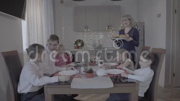 令人惊叹的六人兴奋的家庭在可爱舒适的厨房庆祝活动中享受圣诞晚餐戴着圣诞帽视频的预览图