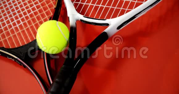 红色地板上网球和球拍的特写视频的预览图