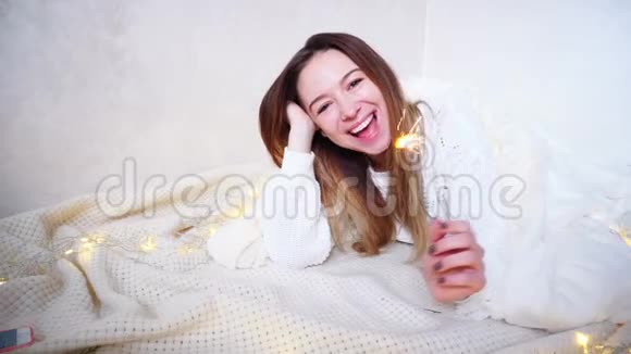 在明亮的房间里躺在铺着毯子地板上充满节日气氛的迷人女孩祝贺新年假期视频的预览图