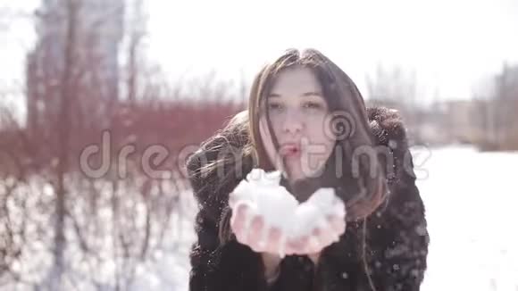 一个美丽可爱的女孩留着深色长发戴着眼镜走在冬天的公园里她微笑着玩雪很开心视频的预览图