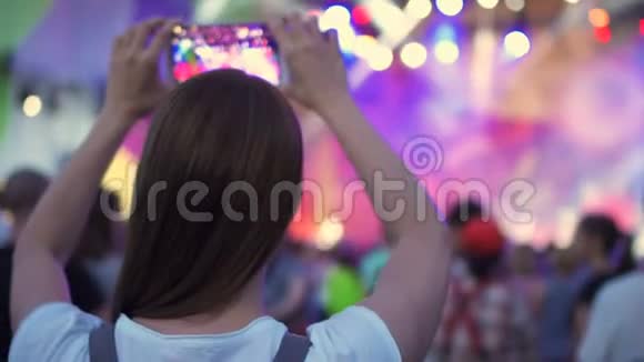露天摇滚音乐会的人群聚会女人站着手里拿着智能手机拍摄视频视频的预览图