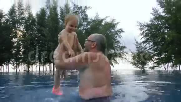 爷爷在游泳池里和小女孩玩视频的预览图
