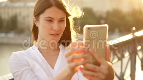 快乐的年轻女人在户外放松漂亮的女孩在智能手机上自拍夏日阳光灿烂视频的预览图