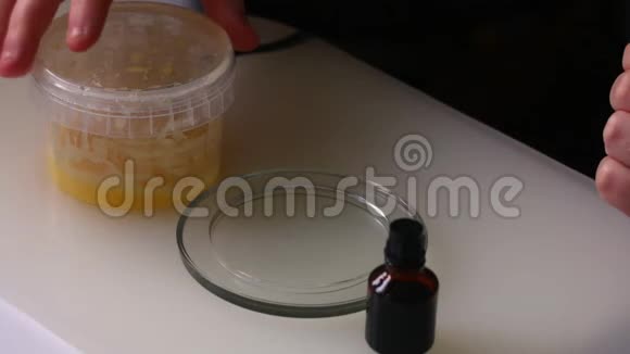 男人检查蜂蜜的质量他把蜂蜜放在玻璃碟上再加几滴碘颜色没有改变视频的预览图