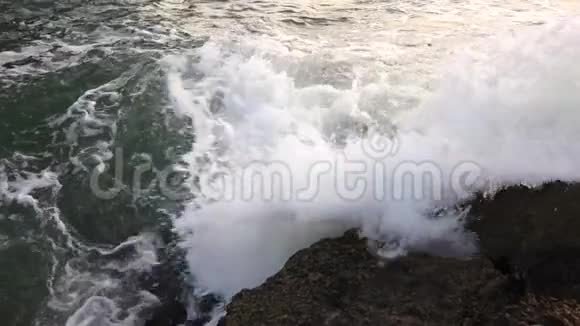 海浪拍打着大海的石岸形成浪花和泡沫慢动作视频的预览图
