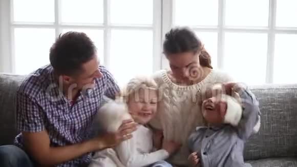 快乐的父母和孩子们在沙发上开心地笑着挠痒痒视频的预览图