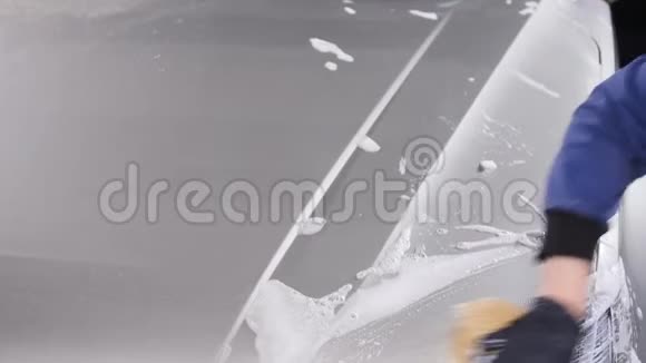 一个男人洗汽车前灯手动洗车的概念视频的预览图