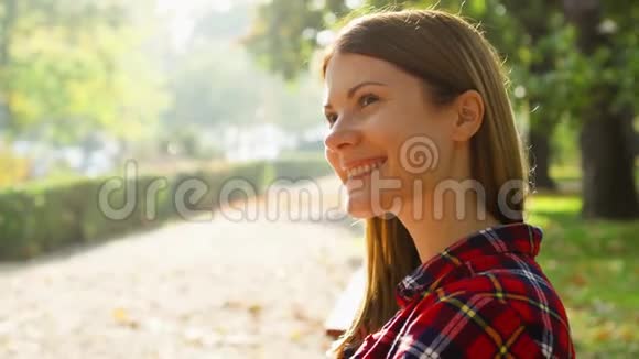 快乐的微笑年轻女人享受大自然坐在绿色公园的长凳上自由孤独概念视频的预览图