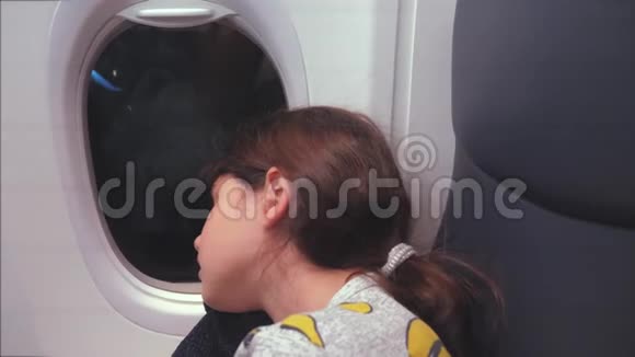 航空飞机概念坐在窗边的小女孩睡在飞机上晚上乘飞机飞行视频的预览图