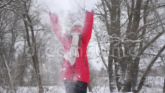 快乐的女孩用双手在森林里扔雪雪在阳光下落下闪闪发光孩子们在公园里玩冬天的游戏视频的预览图