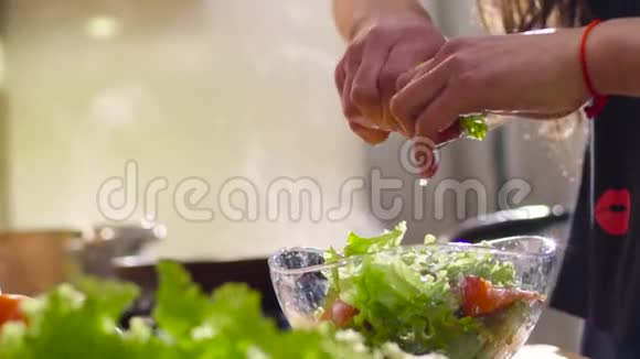 穿着黑色T恤的可爱年轻女人正在厨房做饭她用生菜黄瓜和视频的预览图