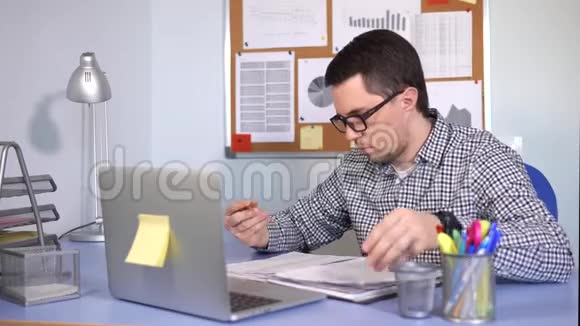 年轻的商人在笔记本电脑上工作并在报纸上写下信息视频的预览图