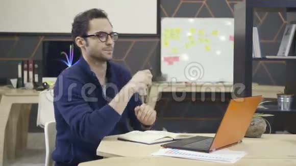 工作场所使用笔记本电脑戴眼镜的创意人视频的预览图