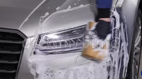 一个男人洗汽车前灯手动洗车的概念视频的预览图