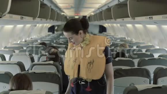 女乘务员穿着救生衣检查飞机上乘客的安全视频的预览图