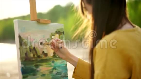 女画家用画笔在她的油画前绘图过程视频的预览图