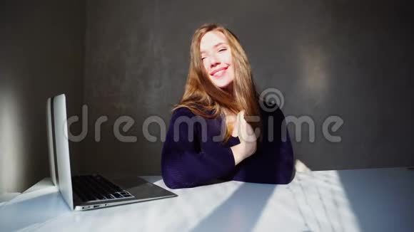 迷人的女孩坐在笔记本电脑附近微笑等待来自英国的电子邮件视频的预览图