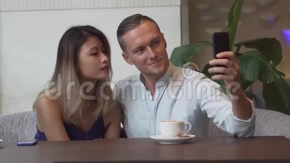 多文化夫妇使用智能手机进行自我画像高加索男人亚洲女人视频的预览图