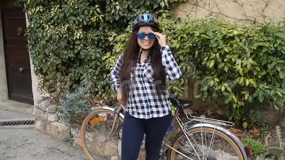 年轻的骑自行车的女性戴着眼镜戴着头盔微笑着看着摄像机视频的预览图