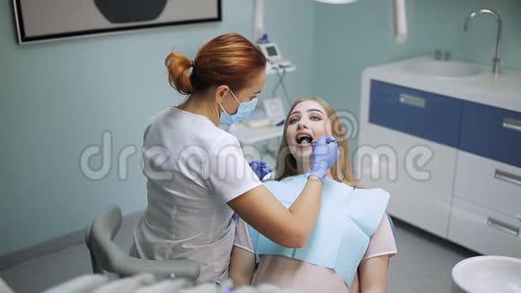 戴口罩的女性口腔医生女医生在工作病人照镜子视频的预览图