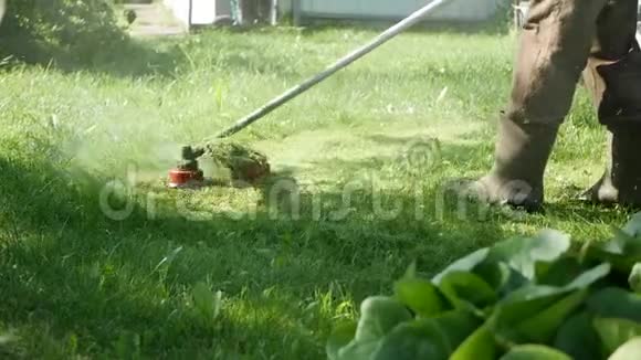 在阳光明媚的夏日一名男性工人正在使用汽油割草机和电动割草机修剪草坪在乡下割草视频的预览图
