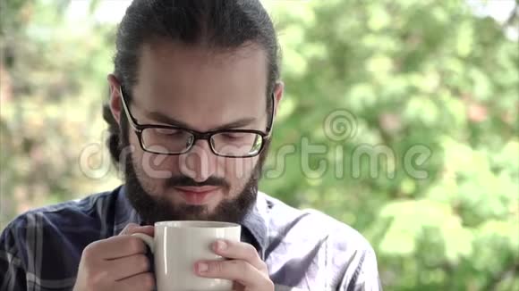 一位年轻的办公室男士的特写肖像享受着一杯新鲜咖啡的味道视频的预览图