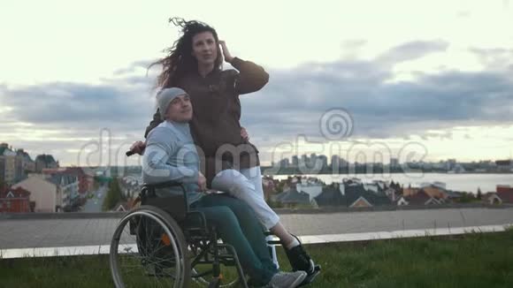 坐轮椅的快乐残疾男子与户外年轻女子拥抱视频的预览图