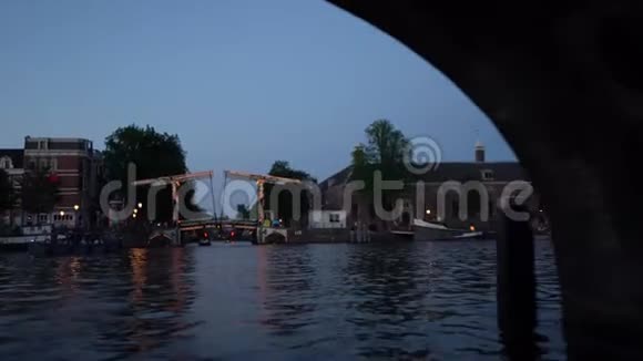 阿姆斯特丹的夜景由照明建筑和路灯装饰的运河经过桥下的船只视频的预览图