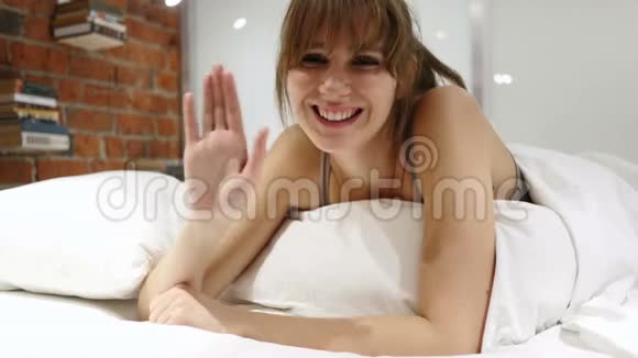 你好欢迎在床上挥手的快乐女人视频的预览图