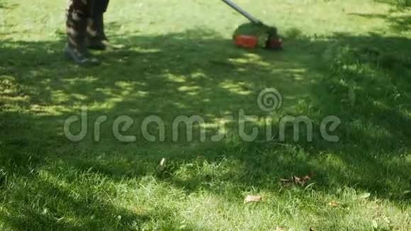 在阳光明媚的夏日一名男性工人正在使用汽油割草机和电动割草机修剪草坪在乡下割草视频的预览图