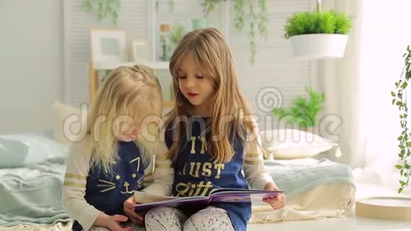 两个小女孩在一个有植物的明亮房间里看书视频的预览图