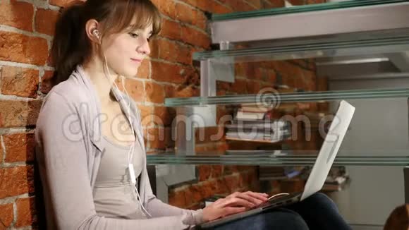 女子听音乐在笔记本电脑和跳舞坐在楼梯视频的预览图