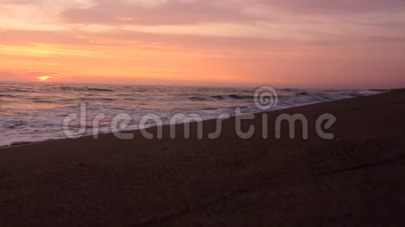 沙滩和美丽的海浪在夕阳的余晖中形成泡沫视频的预览图