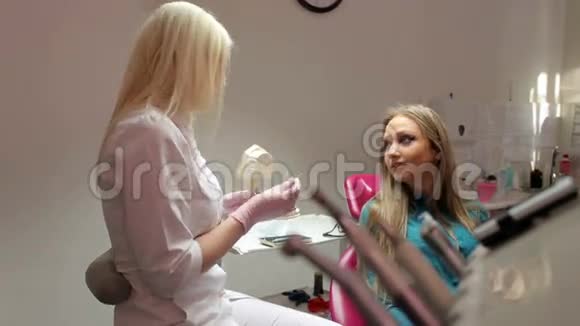 女牙医与病人交谈在牙科办公室展示牙颌模型视频的预览图