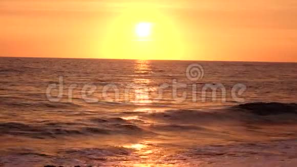 海浪在夕阳的照耀下在沙滩上翻滚视频的预览图