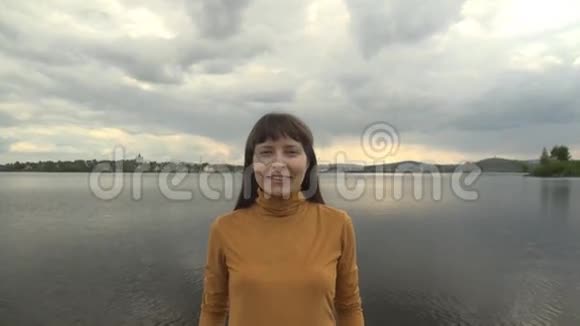 阴天时年轻女子在城市池塘的背景下摆姿势视频的预览图