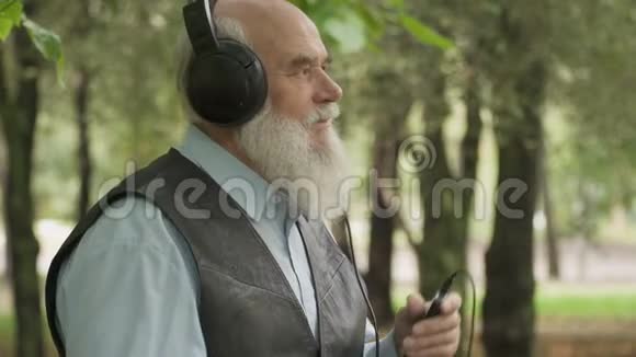 跳舞的老人用耳机听音乐的肖像视频的预览图