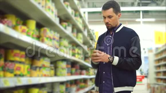 在超市里选罐头蔬菜的男人视频的预览图