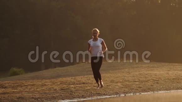 清晨年轻女子沿着海滩奔跑视频的预览图