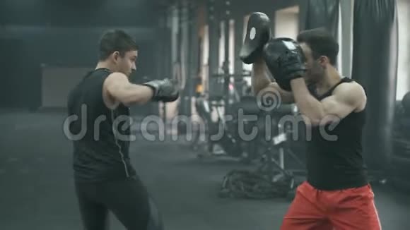 运动员在训练过程中与拳击教练在健身房打架4K慢动作视频的预览图
