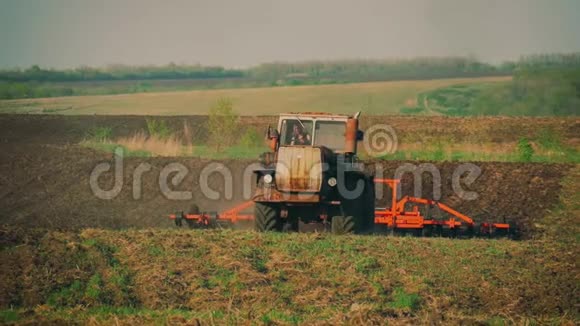 农用拖拉机播种栽培田拖拉机与犁拖车耕田后日落视频的预览图