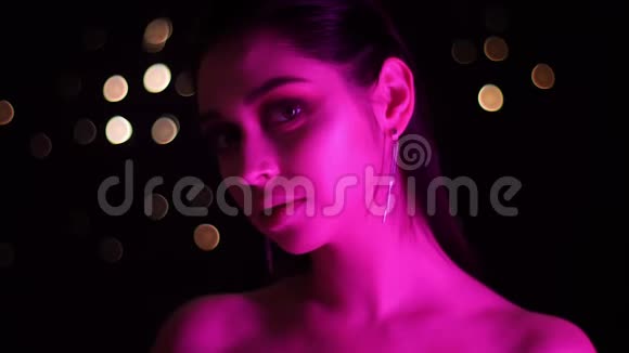 年轻迷人的白种人女性特写镜头带有粉红色霓虹灯和bokeh背景视频的预览图