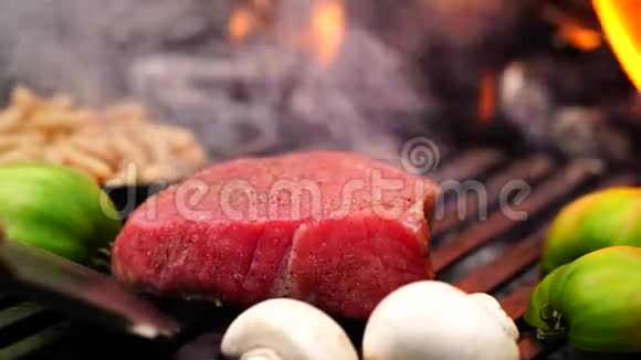 男人用手在烤盘上旋转一大块牛肉牛排粉红色的肉配上新鲜的切菜在森林营地燃烧火焰视频的预览图