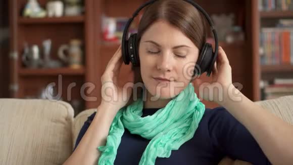 快乐的年轻女子在家听无线无绳耳机音乐唱歌视频的预览图