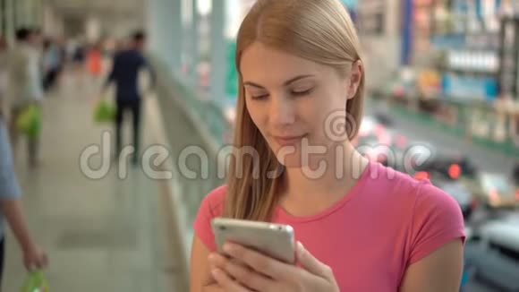 享受城市大街的女人用智能手机站在城市的桥上背景道路视频的预览图