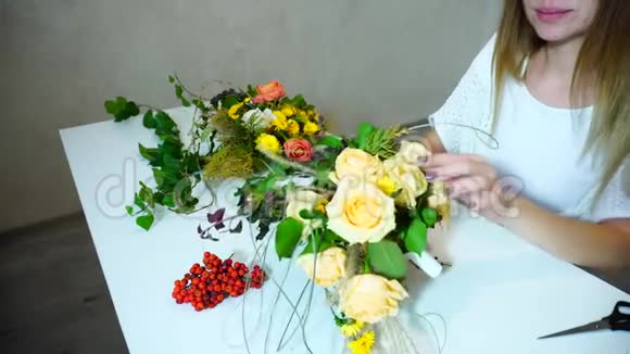 女花匠为新娘花束摘花并在办公室的桌子上做花艺工作视频的预览图