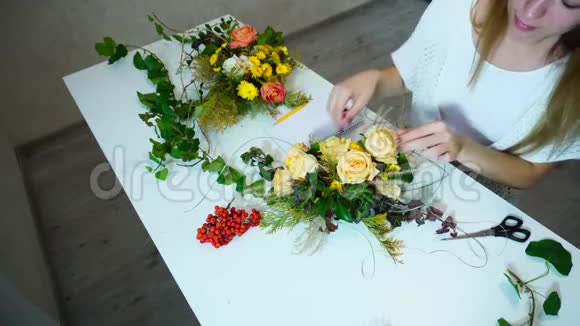 年轻可爱的女设计师用鲜花定制的主题作品创造色彩每天都在办公室的餐桌上视频的预览图