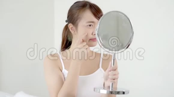 美丽的肖像年轻的亚洲女人照镜子摸脸是痤疮zit治疗视频的预览图